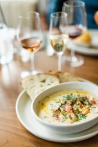 bowl of seafood chowder with rose and white wine